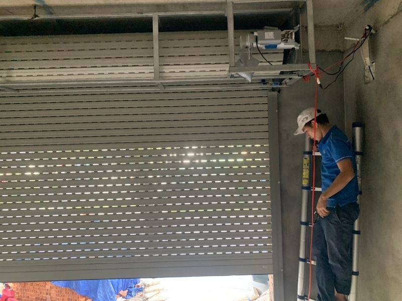 Kỹ thuật viên đang sửa cửa cuốn tại nhà khách hàng ở Hòa Cường